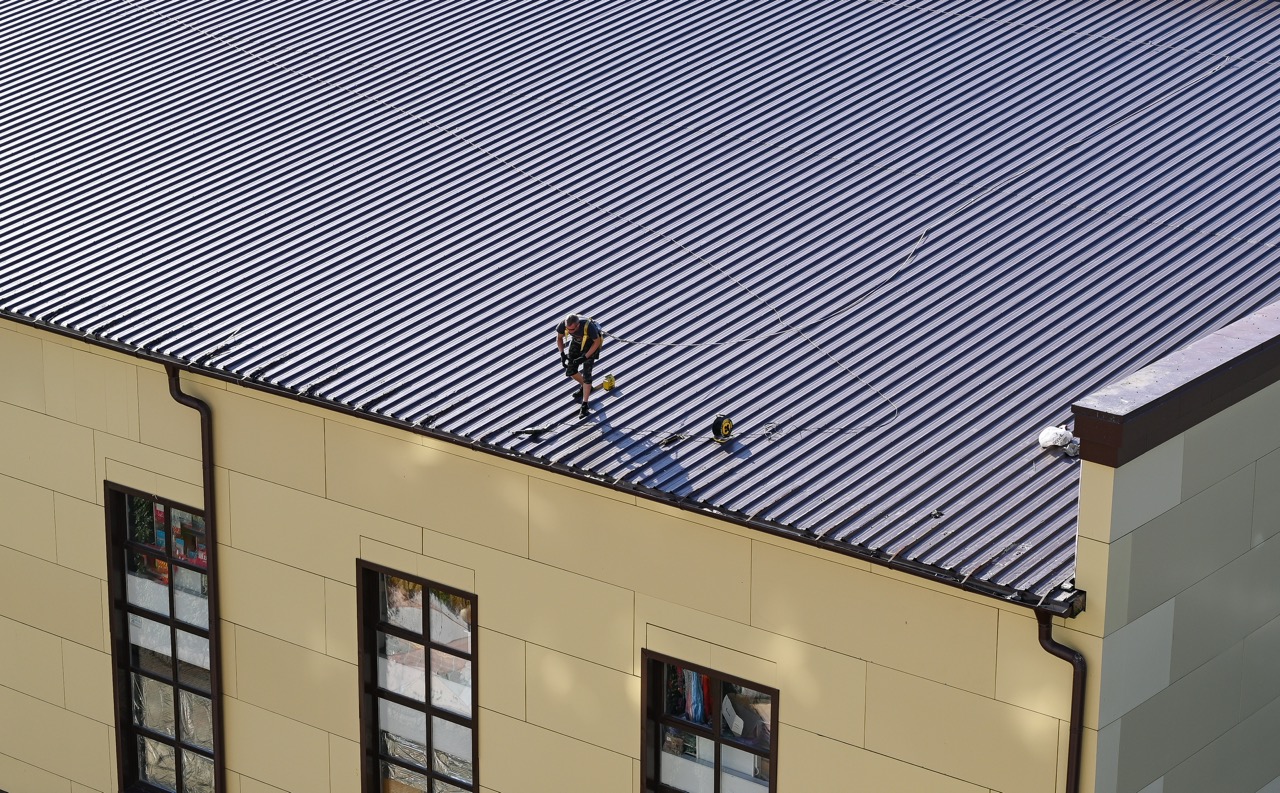 A Craftsman Roofing crew member harnessed and working on a corrugated metal commercial roof in NJ.