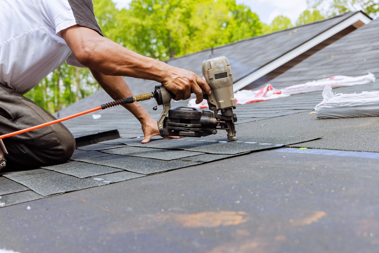 Hand-fastening detail work on a NJ commercial-style roofing project — the kind of close-in work flat-roof terminations require.